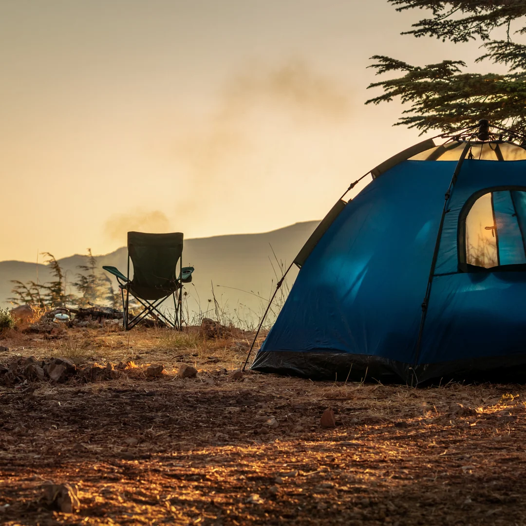A tent and camping chair overlooking a mountain landscape.